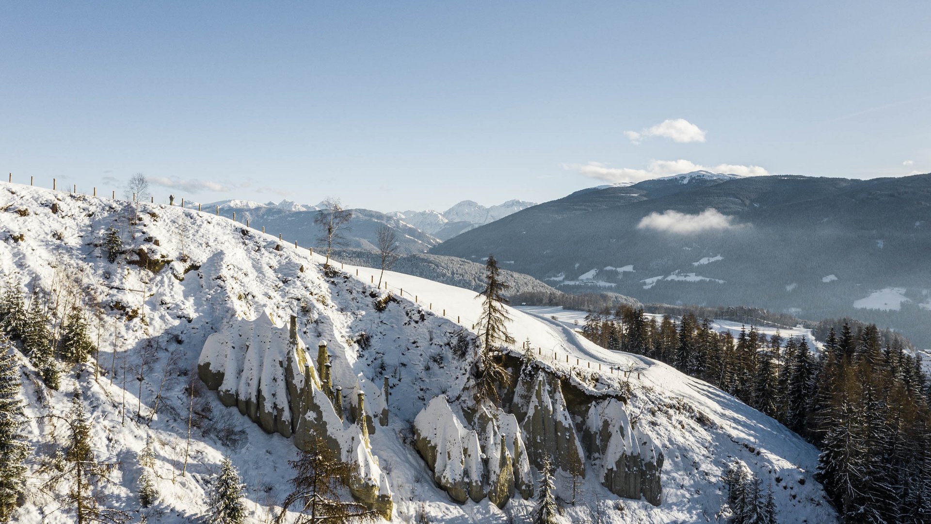 Terento in Val Pusteria Piramidi di terra innevate tra montagne con cielo azzurro
