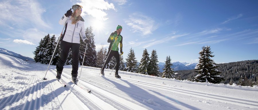 Benvenuti nell’Area Vacanze Sci e Malghe Rio Pusteria! Due persone che fanno sci di fondo su neve soleggiata