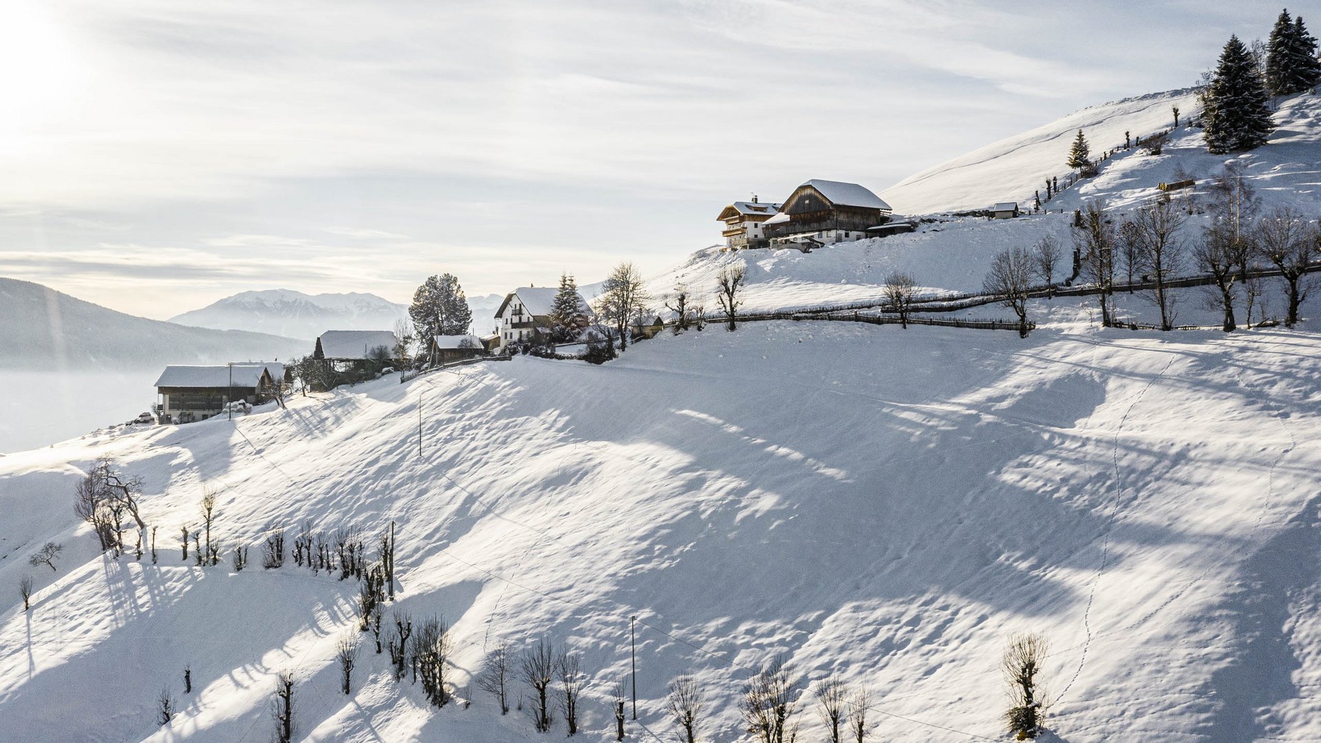 Terento in Val Pusteria Pendii innevati con alcune case sotto un cielo limpido e soleggiato