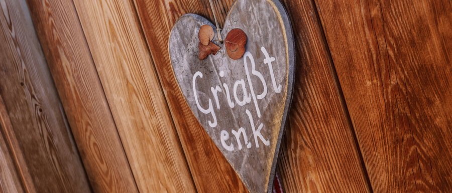 Benvenuti nell’Area Vacanze Sci e Malghe Rio Pusteria! Un cuore di legno con l'iscrizione "Griaßt enk"