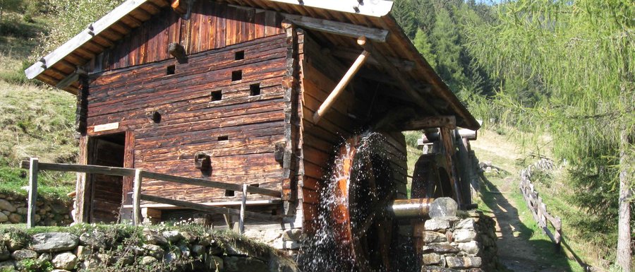 Benvenuti nell’Area Vacanze Sci e Malghe Rio Pusteria! Mulino ad acqua di legno in paesaggio montano boscoso