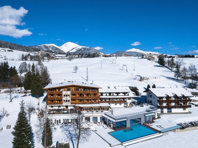 Benvenuti nell’Area Vacanze Sci e Malghe Rio Pusteria! Hotel con piscina esterna in paesaggio montano innevato sotto cielo azzurro