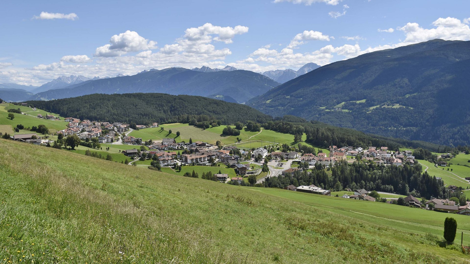 Terento in Val Pusteria Vista di un villaggio in una valle verde con montagne e cielo azzurro
