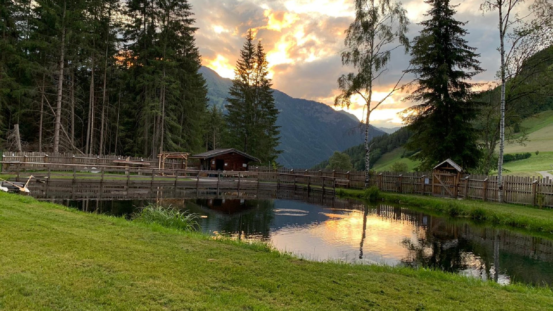 Terento in Val Pusteria Tramonto su uno stagno con alberi e montagne sullo sfondo