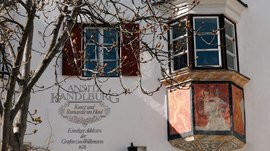 Alla scoperta di Rio di Pusteria Balcone affrescato e finestre su edificio storico bianco con albero davanti