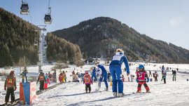 Valles & il villaggio alpino più bello dell’Alto Adige Bambini imparano a sciare su una pista per principianti con istruttori