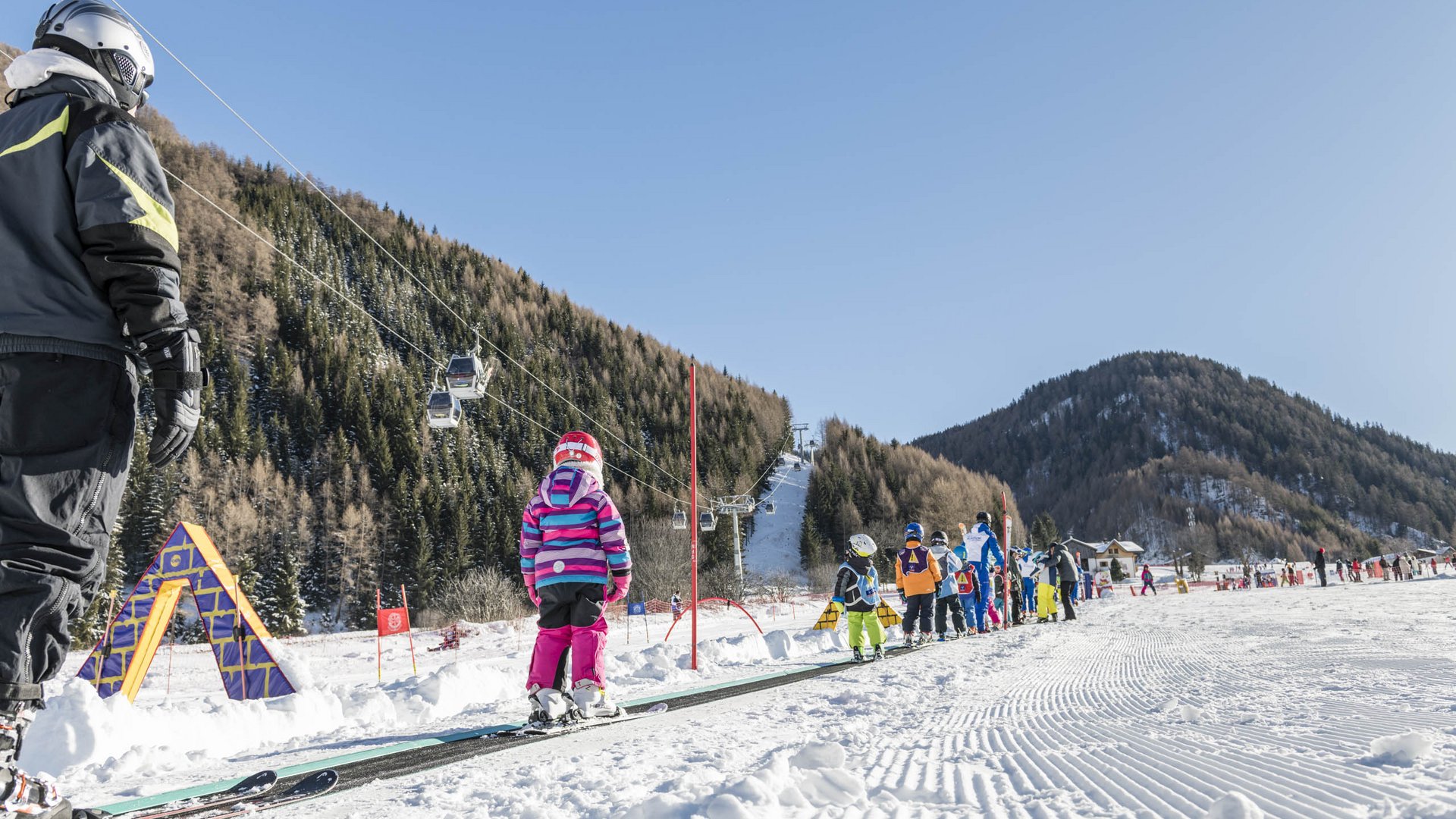 Valles & il villaggio alpino più bello dell’Alto Adige Bambini imparano a sciare su un tapis roulant in una stazione sciistica montana