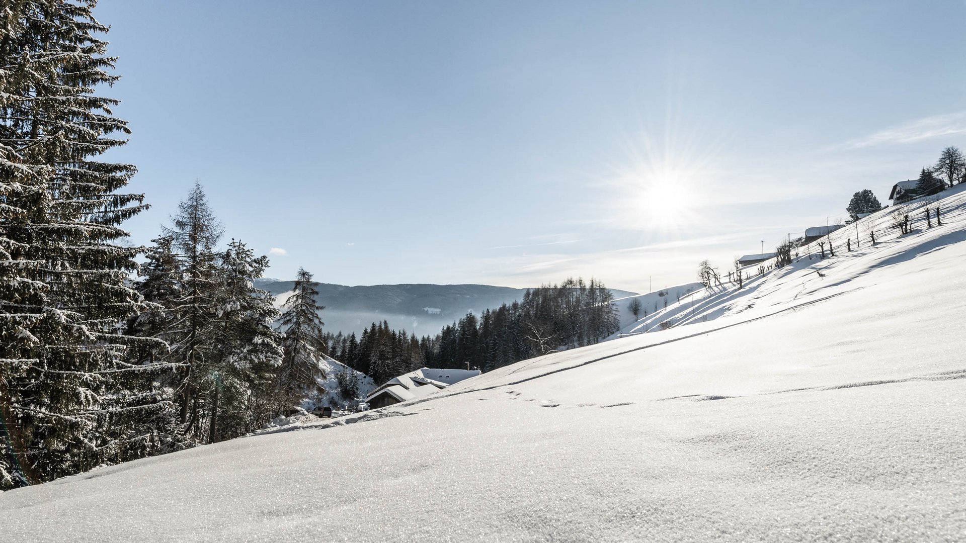 Terento in Val Pusteria Paesaggio invernale innevato con alberi e case sotto il sole