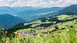Terento in Val Pusteria Vista di un villaggio in una verde valle collinare con montagne sullo sfondo