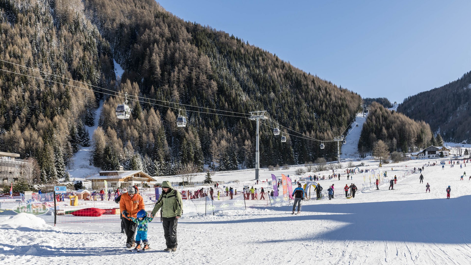 Valles & il villaggio alpino più bello dell’Alto Adige Stazione sciistica con persone, seggiovie e montagne innevate sotto cielo sereno