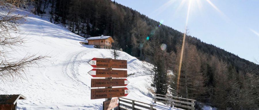 Benvenuti nell’Area Vacanze Sci e Malghe Rio Pusteria! Cartello escursionistico in un paesaggio innevato della valle Alpbach con sole brillante